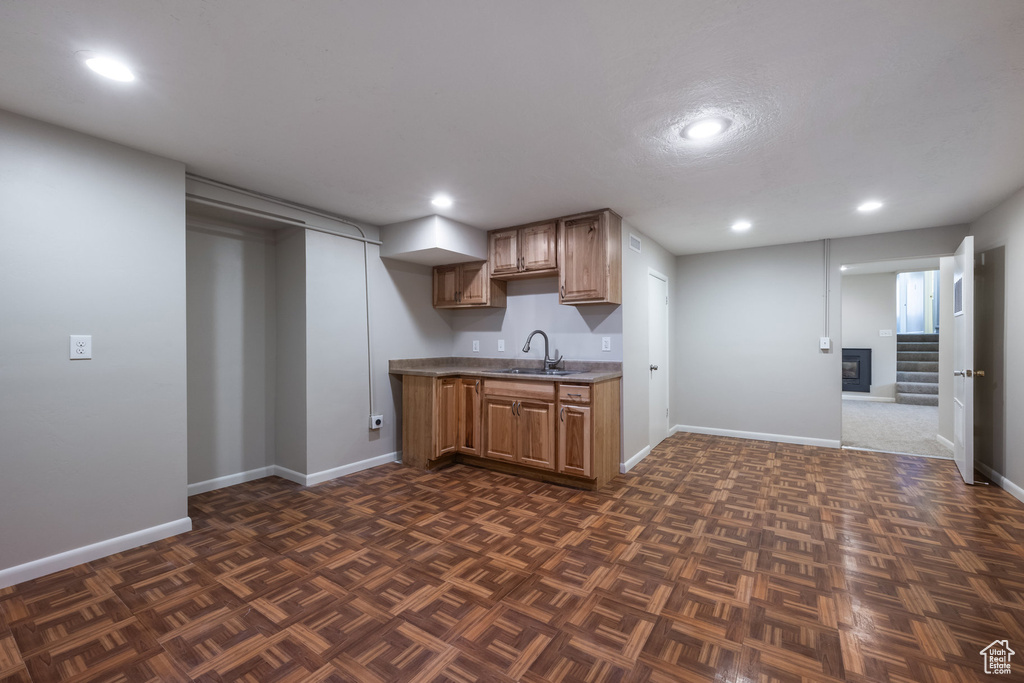 Kitchen featuring a sink, light countertops, brown cabinetry, recessed lighting, and baseboards