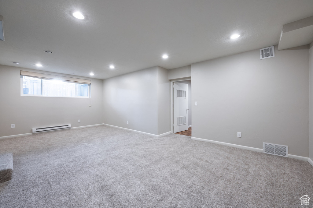 Below grade area with visible vents, a baseboard radiator, carpet flooring, and recessed lighting