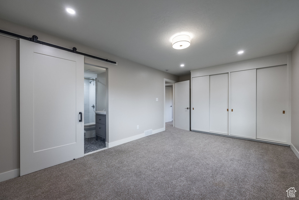 Unfurnished bedroom with carpet, a closet, recessed lighting, and a barn door