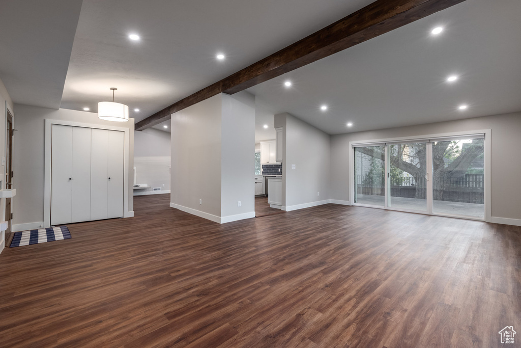 Unfurnished living room featuring recessed lighting, baseboards, vaulted ceiling with beams, and dark wood-style flooring