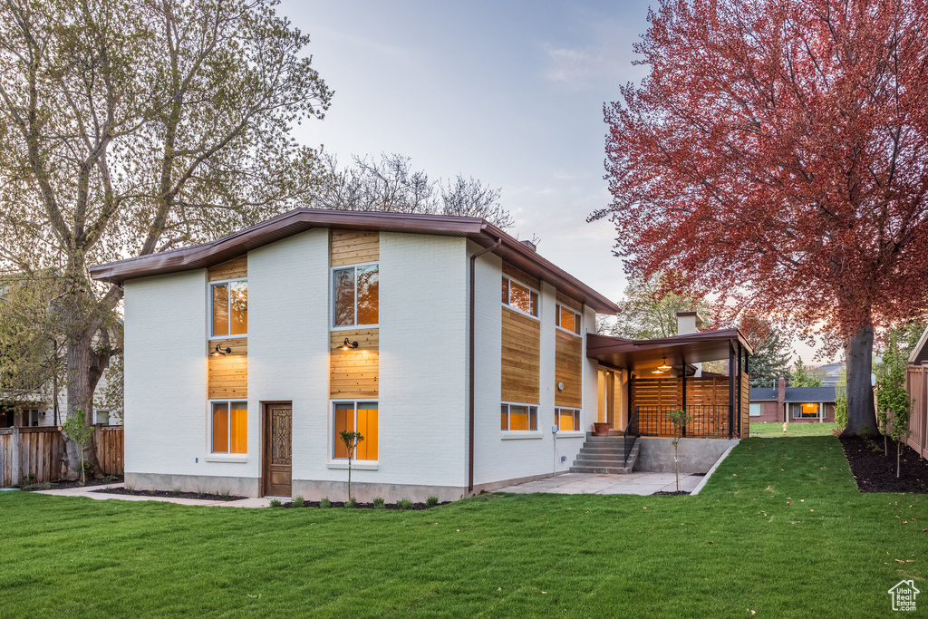 Rear view of property with a yard, brick siding, fence, and a patio