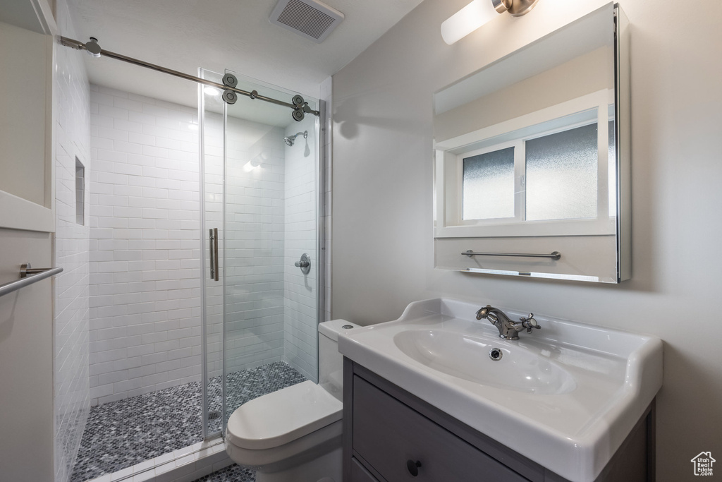 Full bathroom with vanity, a stall shower, toilet, and visible vents