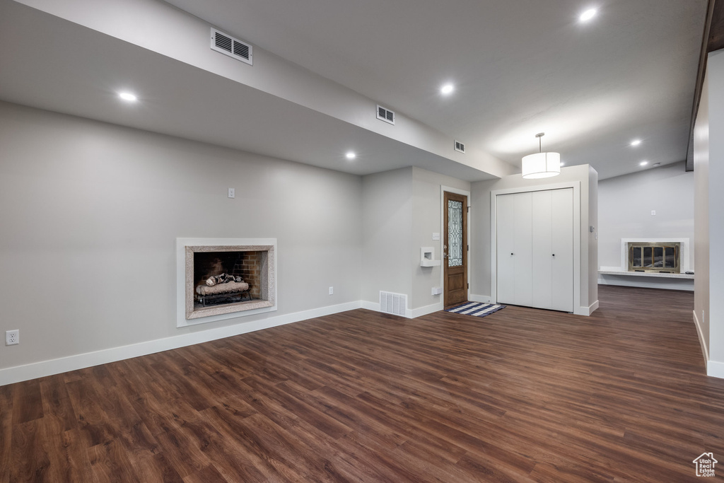 Unfurnished living room with baseboards, a fireplace, dark wood finished floors, and visible vents