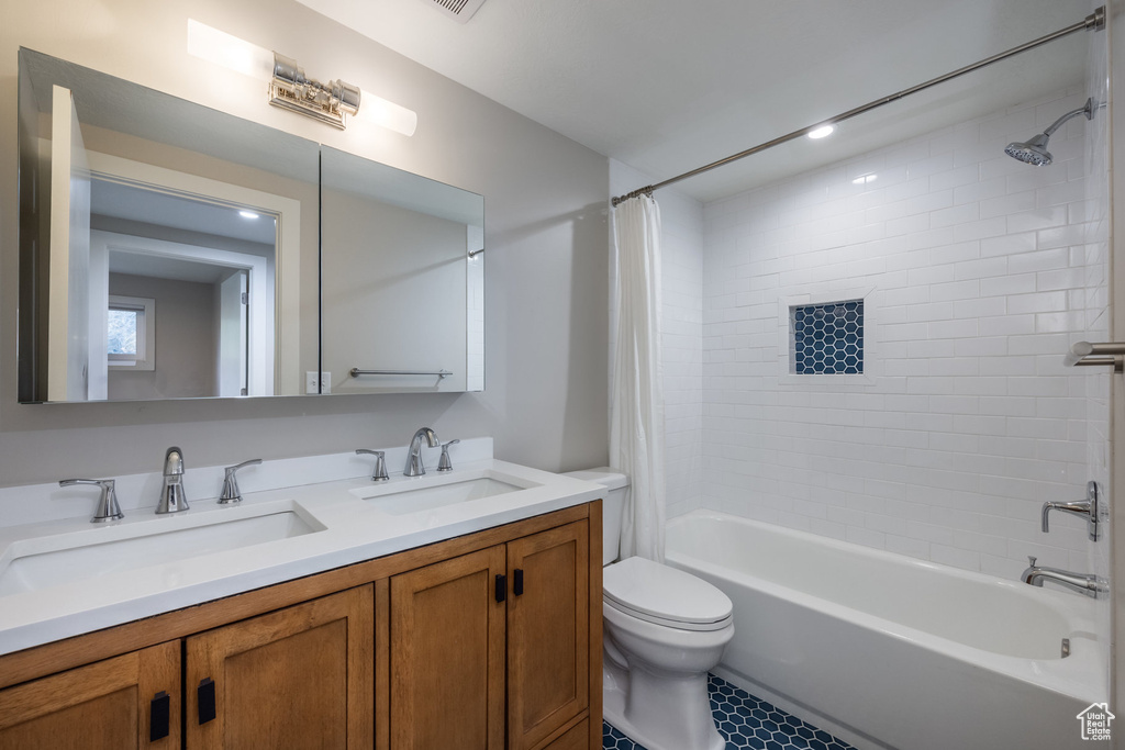 Bathroom with double vanity, shower / bath combo with shower curtain, toilet, and a sink