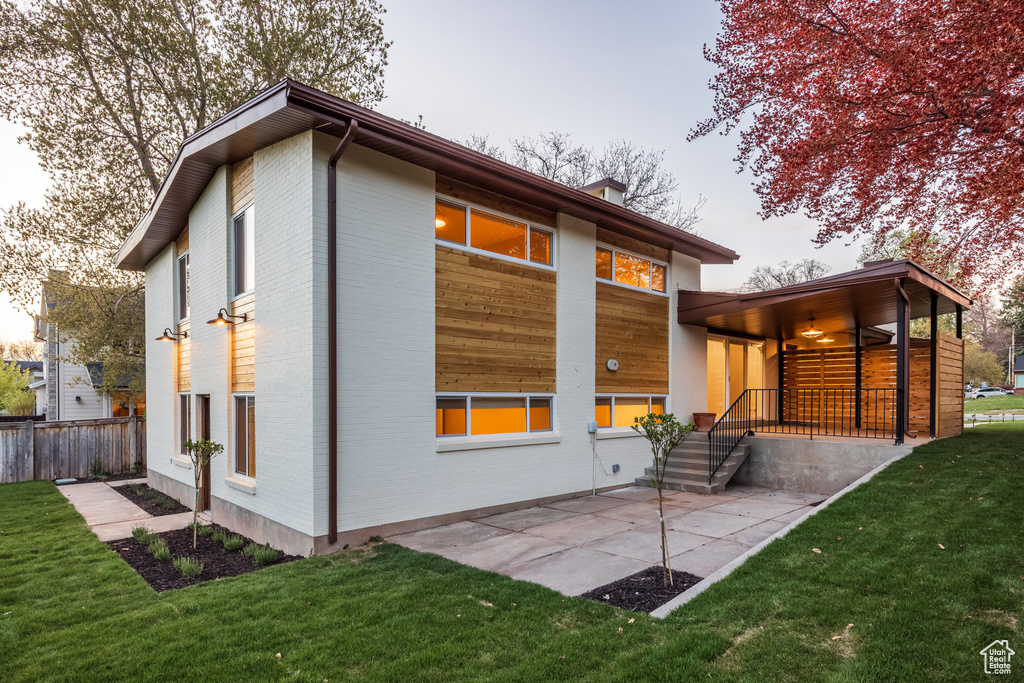 Rear view of house featuring a patio, fence, a yard, and brick siding