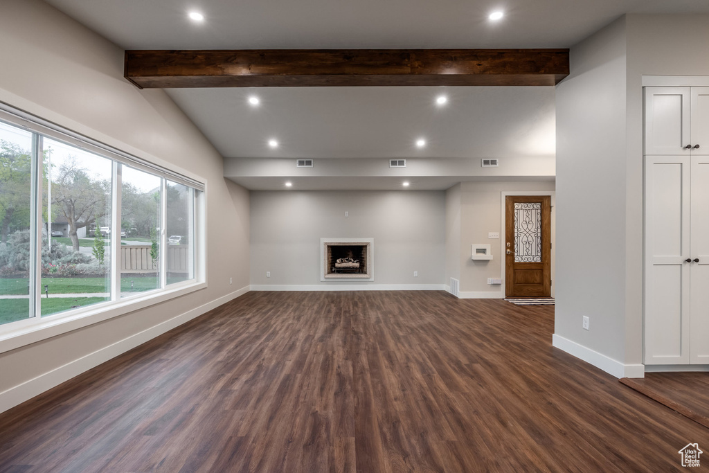 Unfurnished living room with baseboards, dark wood finished floors, and a wealth of natural light