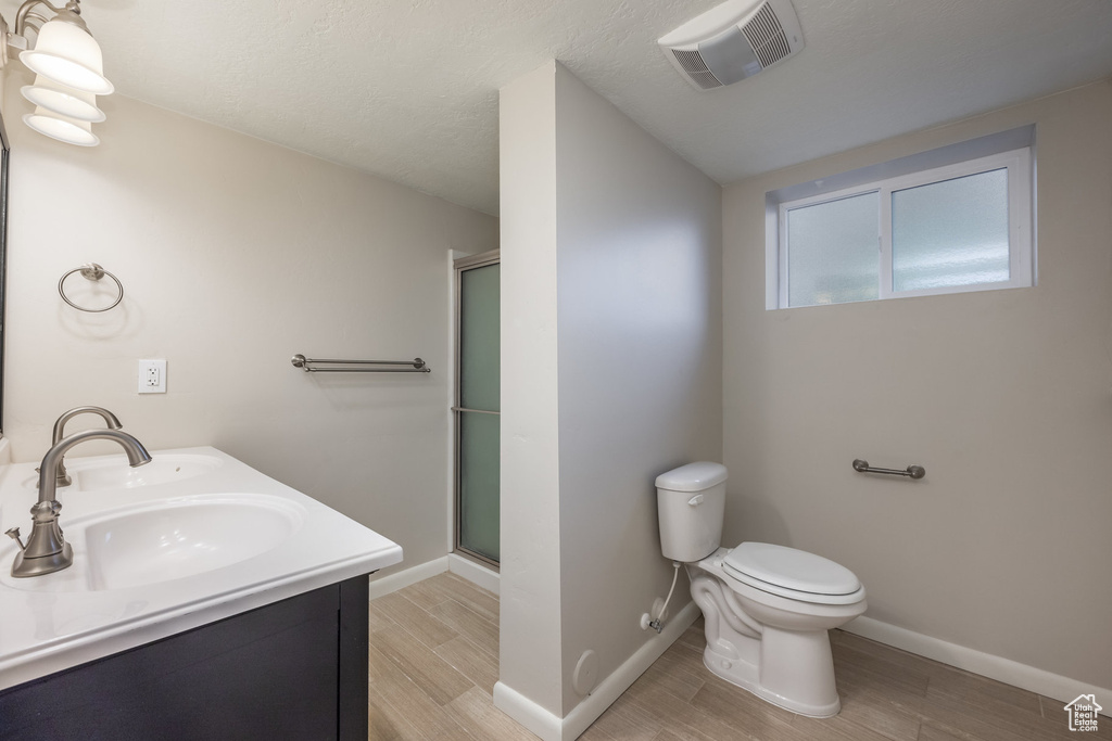 Bathroom featuring toilet, visible vents, a shower stall, and a sink