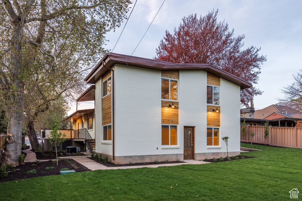 Rear view of property featuring fence, a yard, a deck, and cooling unit