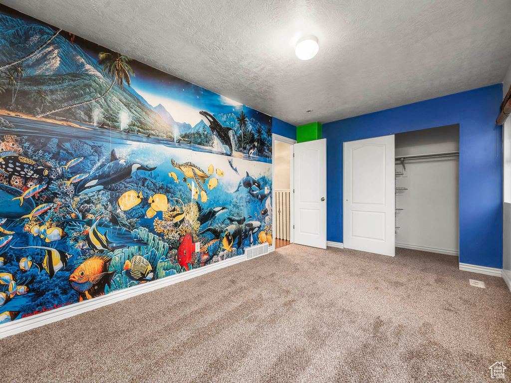 Unfurnished bedroom featuring carpet floors, a closet, baseboards, visible vents, and a textured ceiling