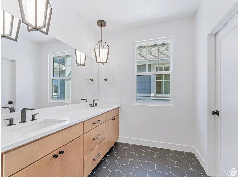 Full bath featuring double vanity, a sink, baseboards, and tile patterned flooring