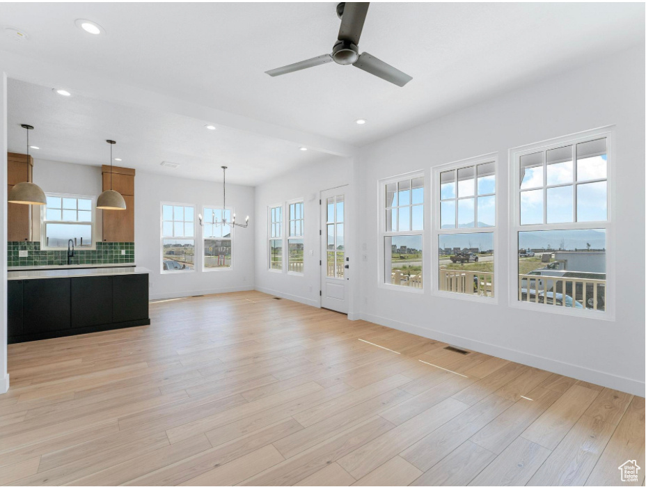 Unfurnished living room featuring a sink, ceiling fan with notable chandelier, recessed lighting, and light wood-style flooring