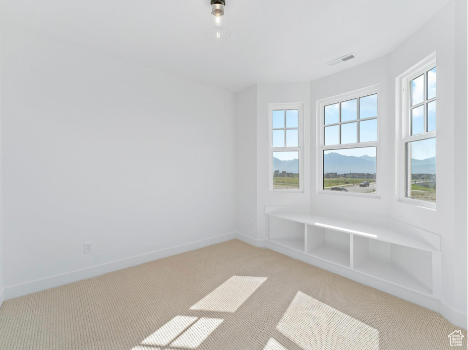 Empty room with baseboards, visible vents, and light carpet