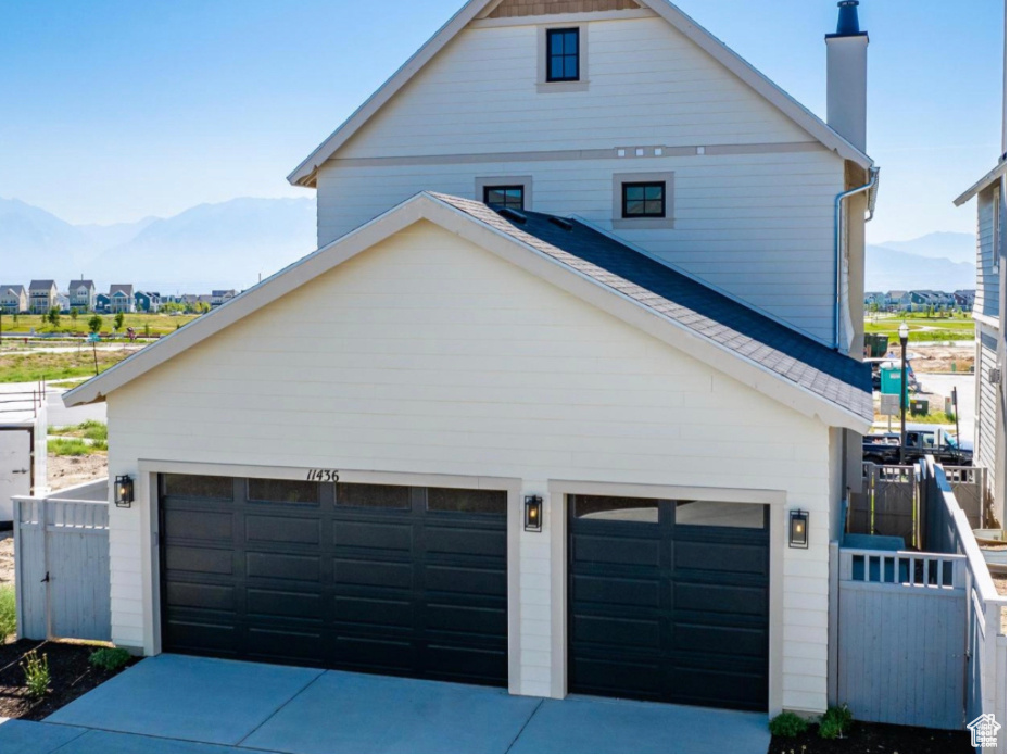 View of side of home with driveway, fence, a chimney, and a mountain view