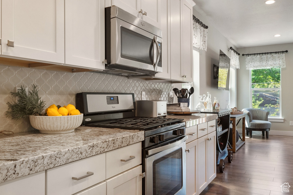 Kitchen featuring stainless steel appliances, recessed lighting, white cabinetry, tasteful backsplash, and dark wood-type flooring