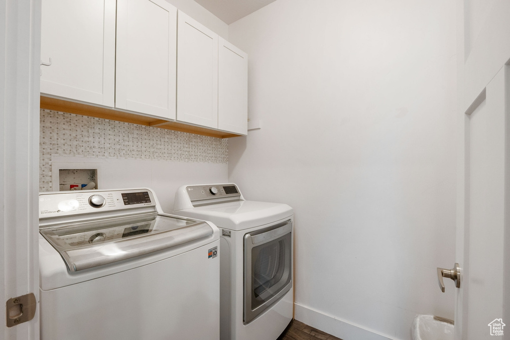 Clothes washing area featuring baseboards, cabinet space, independent washer and dryer, and wood finished floors