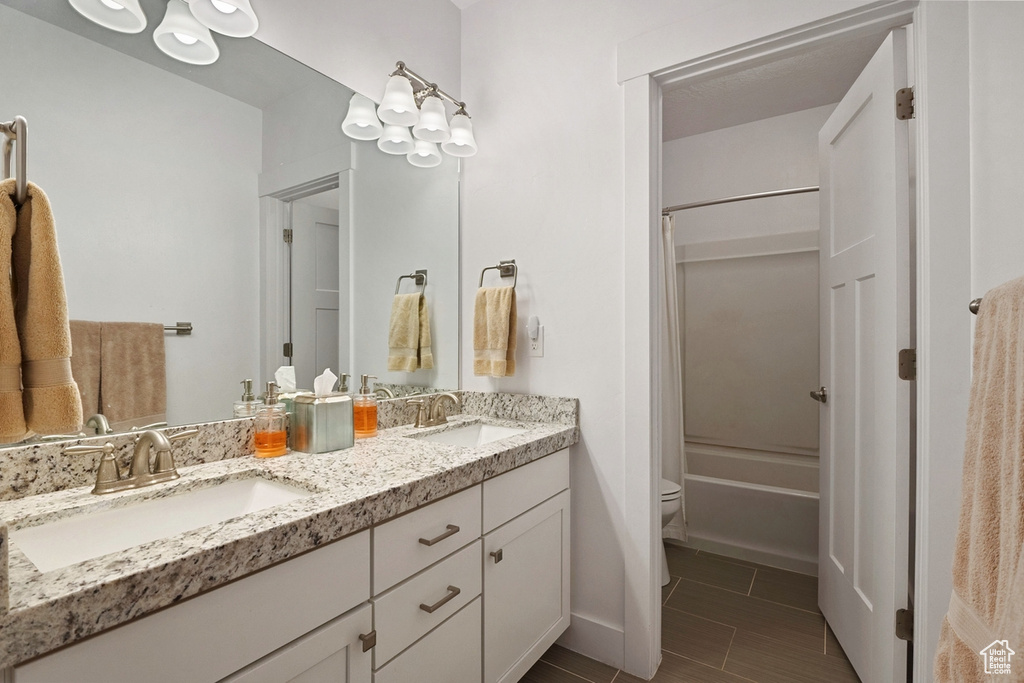 Bathroom featuring double vanity, a sink, shower / bath combo, and toilet