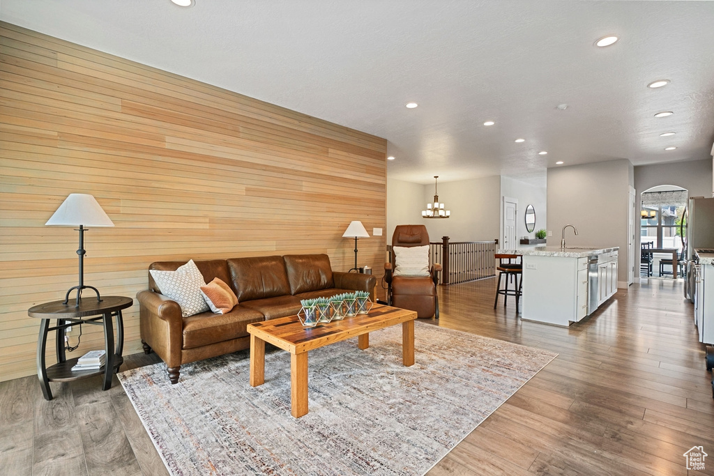 Living area with arched walkways, wood walls, recessed lighting, and wood finished floors