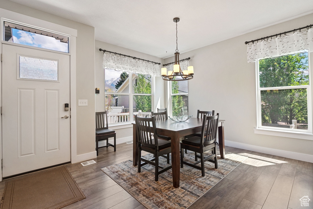 Dining space featuring wood finished floors, baseboards, a chandelier, and visible vents