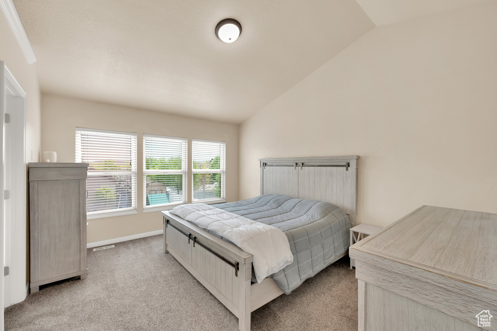 Bedroom featuring light colored carpet, baseboards, and lofted ceiling