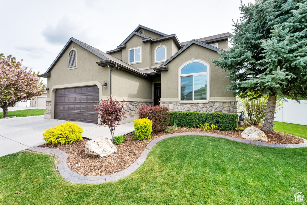 Craftsman-style home with a front lawn, stone siding, a garage, stucco siding, and concrete driveway