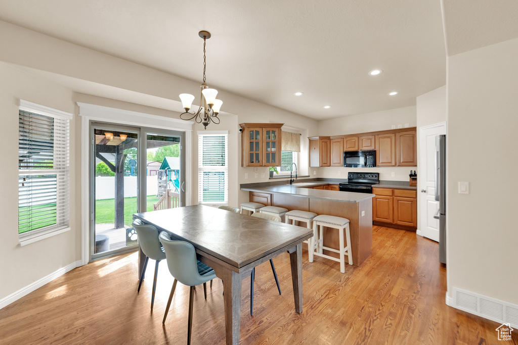 Dining room with an inviting chandelier, baseboards, light wood-type flooring, and a wealth of natural light