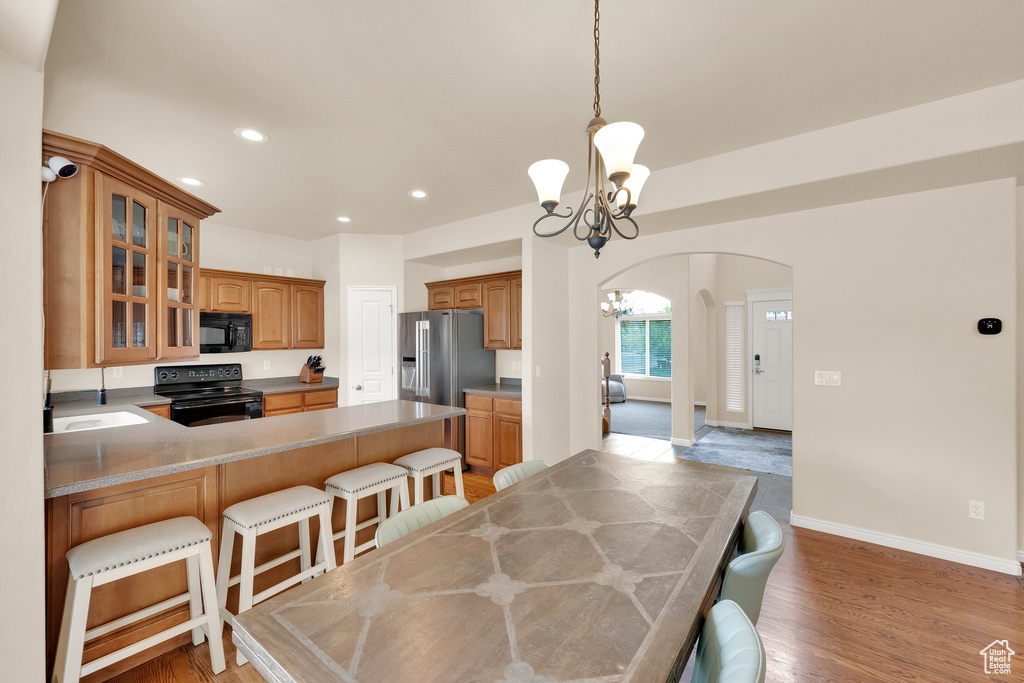 Dining space featuring arched walkways, baseboards, light wood finished floors, a notable chandelier, and recessed lighting