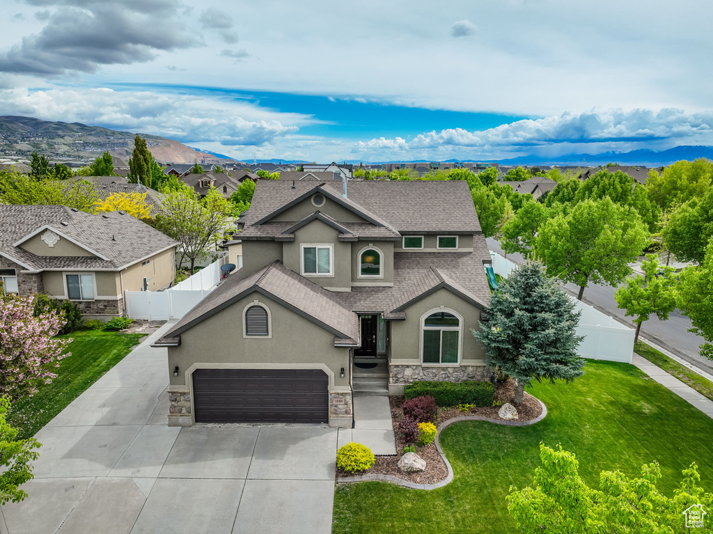 Traditional home with roof with shingles, fence, concrete driveway, stone siding, and stucco siding