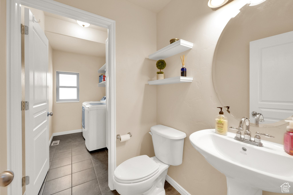 Bathroom with independent washer and dryer, toilet, baseboards, and a sink