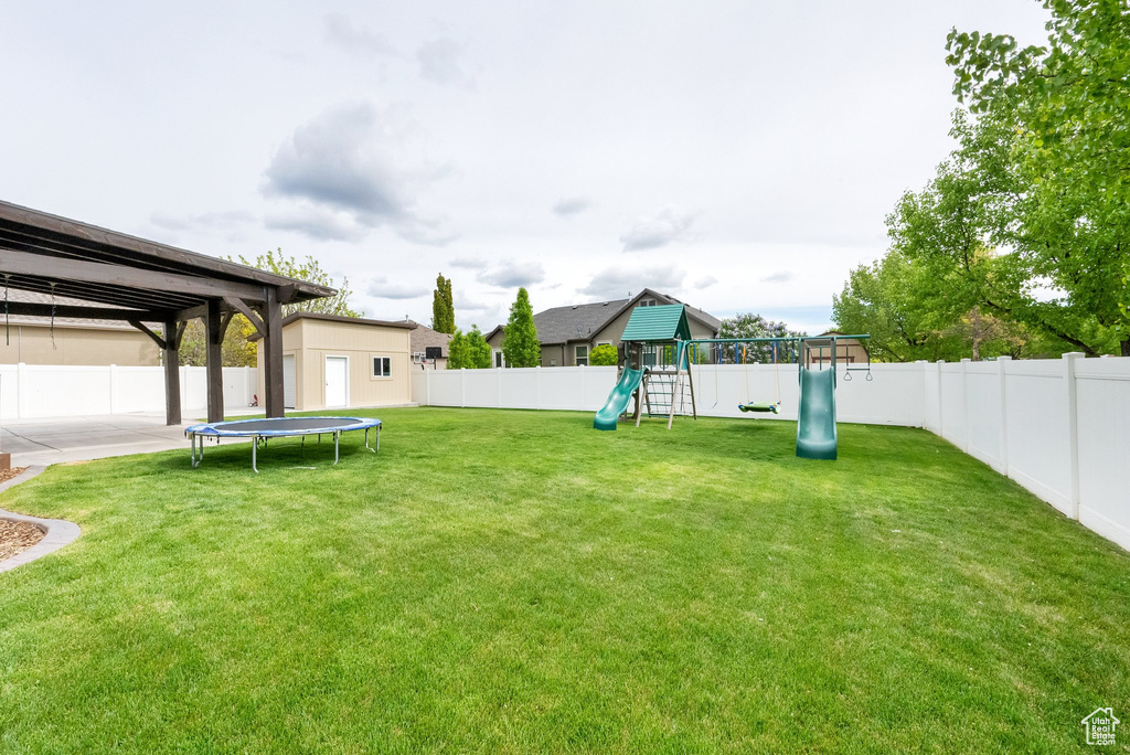 View of yard with a playground, a fenced backyard, and a trampoline