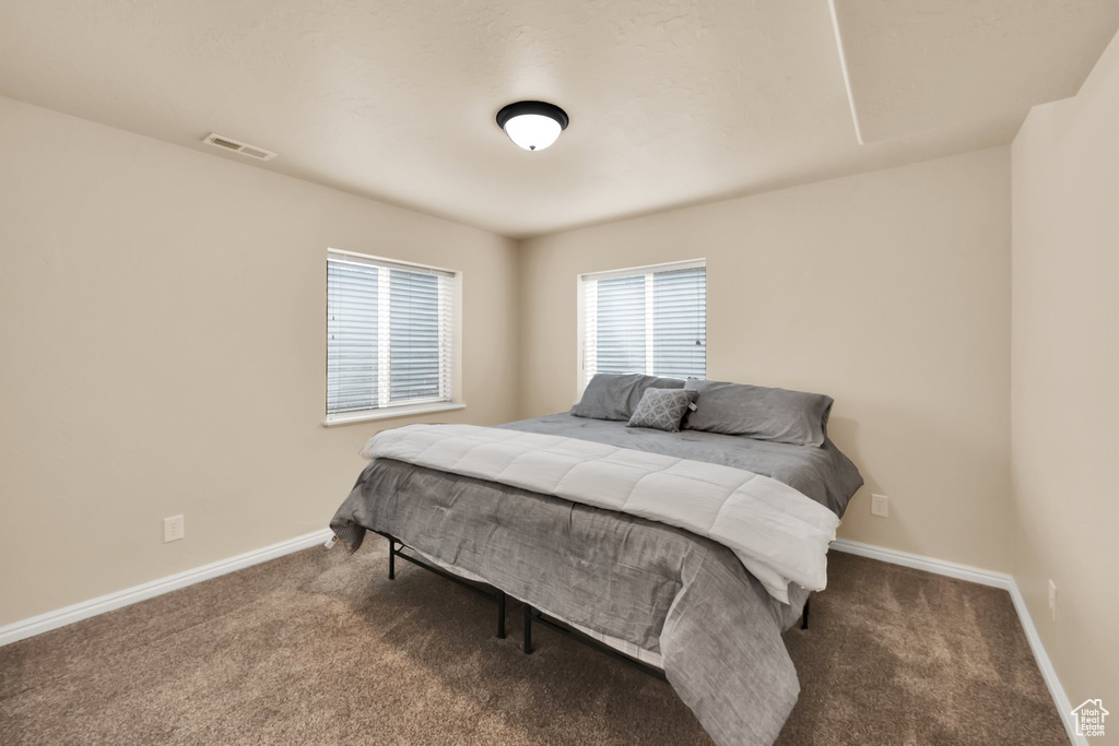 Carpeted bedroom featuring visible vents and baseboards