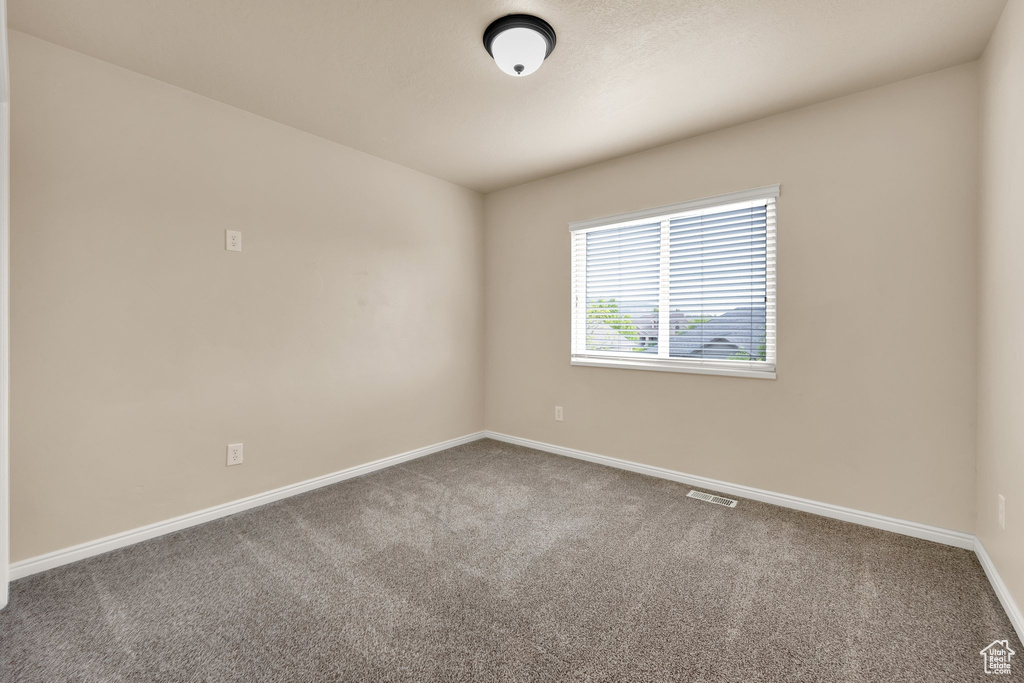 Empty room featuring baseboards, visible vents, and carpet
