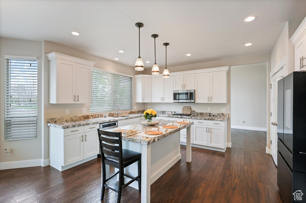 Kitchen with a sink, appliances with stainless steel finishes, plenty of natural light, and white cabinetry