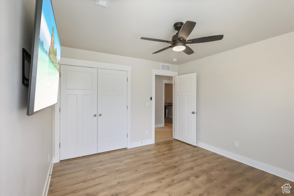 Unfurnished bedroom featuring baseboards, light wood-style flooring, visible vents, and a closet
