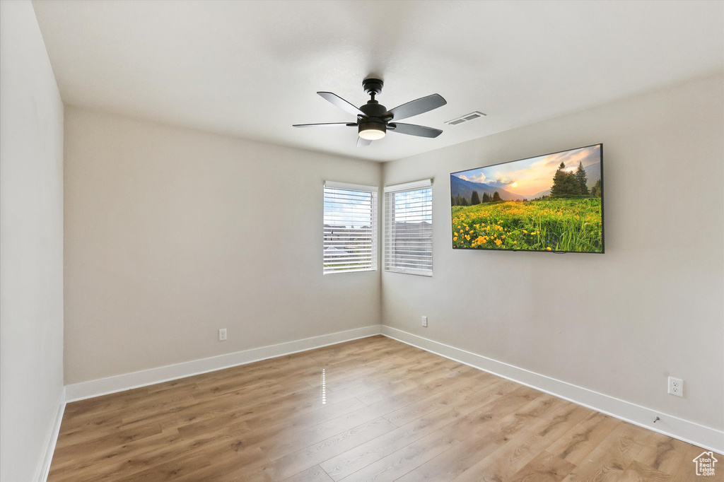 Empty room with visible vents, light wood-style flooring, ceiling fan, and baseboards