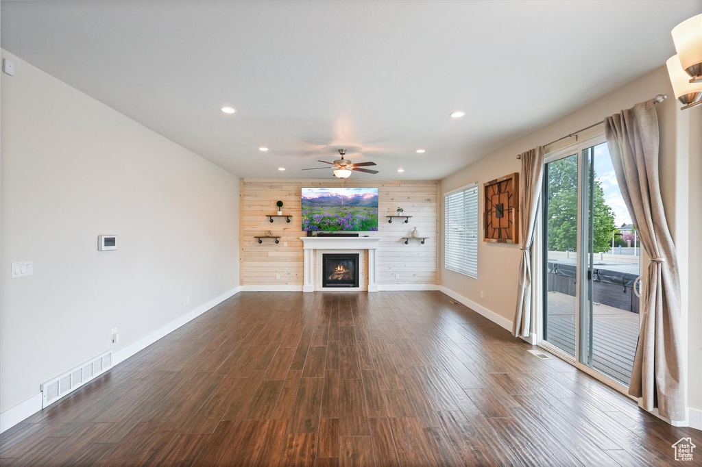 Unfurnished living room with a glass covered fireplace, a ceiling fan, baseboards, recessed lighting, and visible vents