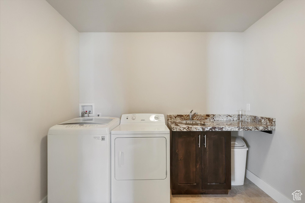 Laundry room with cabinet space, baseboards, washing machine and dryer, and a sink