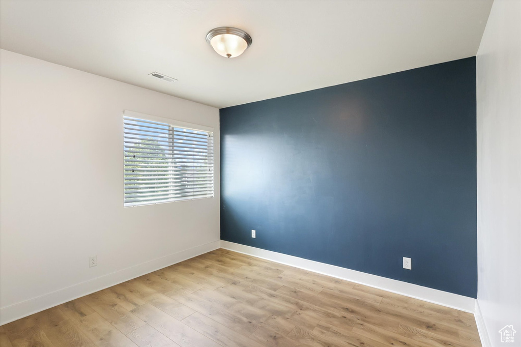 Spare room featuring baseboards, light wood-type flooring, and visible vents