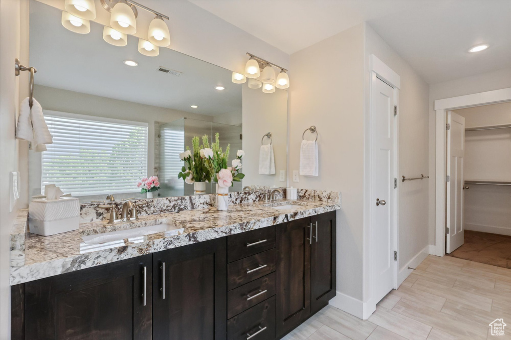 Bathroom with double vanity, a walk in closet, visible vents, and a sink