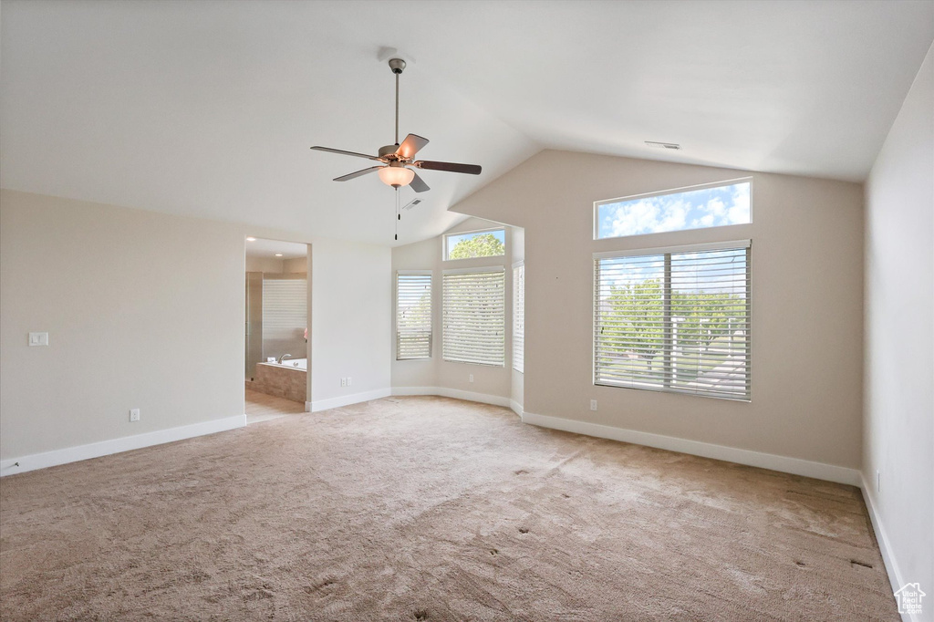 Spare room with a ceiling fan, baseboards, light carpet, and high vaulted ceiling