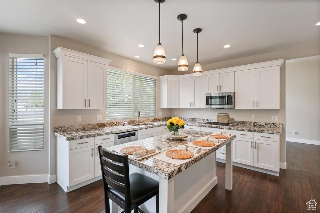 Kitchen with baseboards, white cabinetry, a kitchen bar, and stainless steel appliances