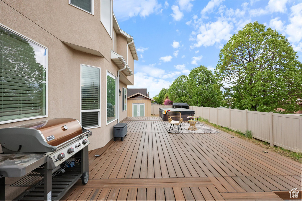 Wooden terrace featuring grilling area, a storage shed, an outdoor structure, a fenced backyard, and outdoor dining space