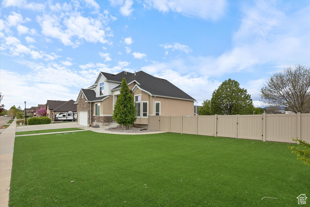 View of property exterior with a lawn, fence, concrete driveway, and a gate