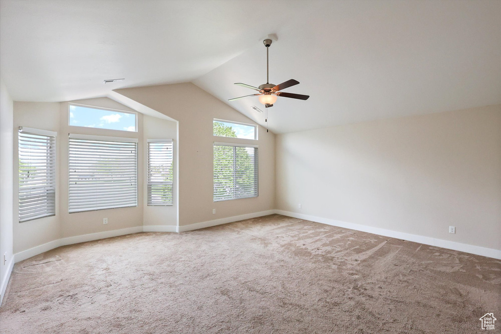 Spare room featuring baseboards, ceiling fan, carpet flooring, and lofted ceiling