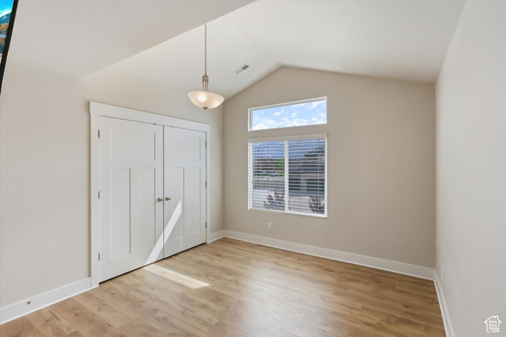 Unfurnished bedroom with visible vents, vaulted ceiling, light wood-type flooring, baseboards, and a closet