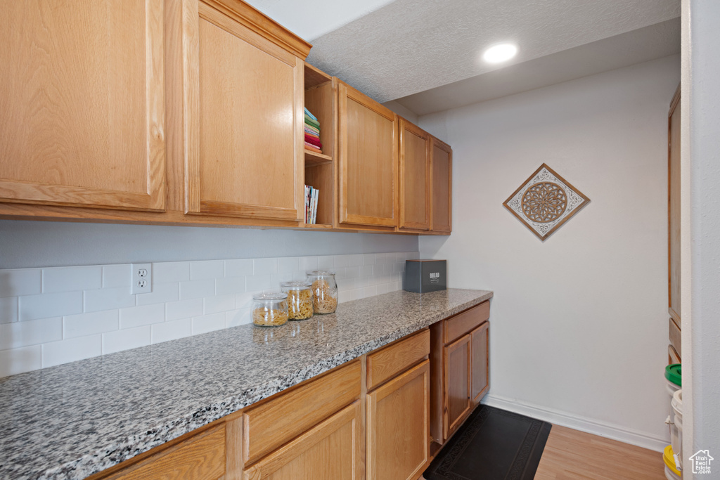 Kitchen featuring backsplash, open shelves, baseboards, light stone counters, and recessed lighting