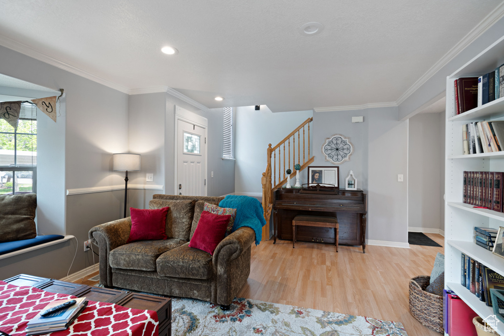 Living room with baseboards, ornamental molding, wood finished floors, and stairway