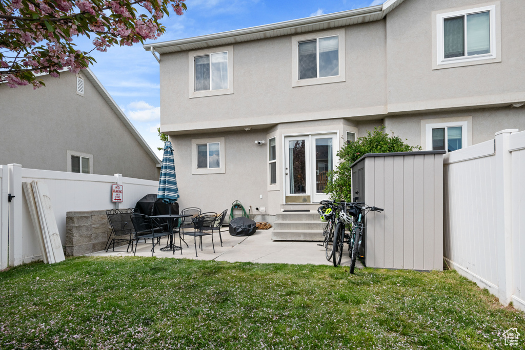 Back of house with a lawn, a fenced backyard, entry steps, and stucco siding