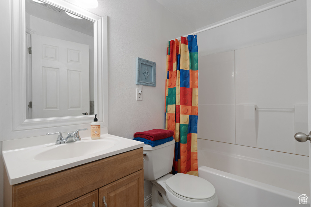 Bathroom featuring toilet, visible vents, shower / bath combo, and vanity