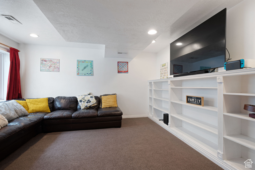 Carpeted living area with visible vents, recessed lighting, a textured ceiling, and baseboards
