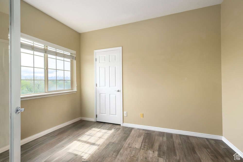 Unfurnished bedroom featuring baseboards and dark wood-type flooring